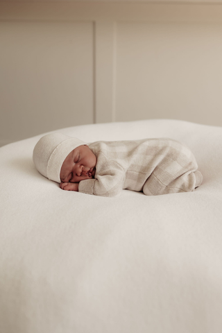 baby asleep on beanbag wearing a knitted hat and romper