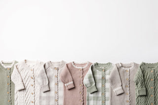 Wooden rail with neutral knitted baby rompers on wooden hangers