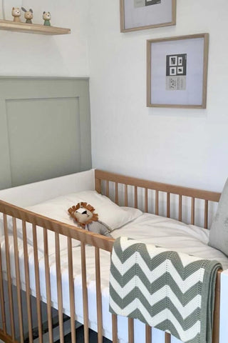 Baby's Nursery with Organic Cotton Sage Chevron Knit Baby Blanket over cot