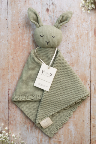 Organic Cotton Isla Bunny Comforter in Sage on a wooden backdrop with gypsophilia