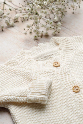 Close up of Moss Stitch Romper on a wood backdrop with flowers