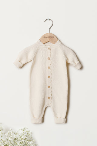 Cream Organic Cotton Baby Romper on an Isla & Fraser Hanger on a white wall 