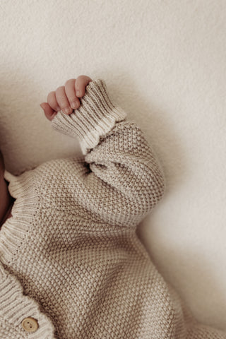 baby wearing knitted beige romper with cream cuffs