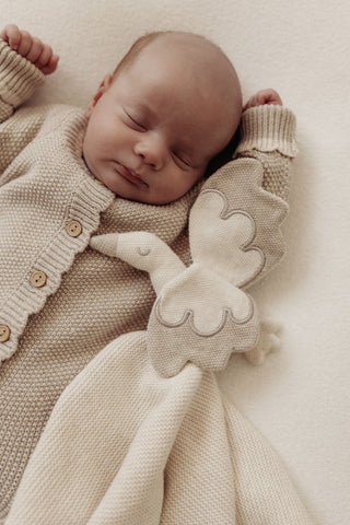 Sleeping baby with cream and grey knitted stork comforter