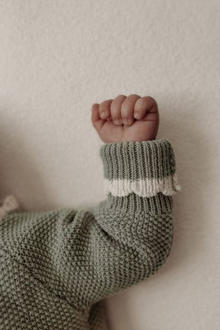 Knitted baby cuff in sage green with contrast cream scalloped edge