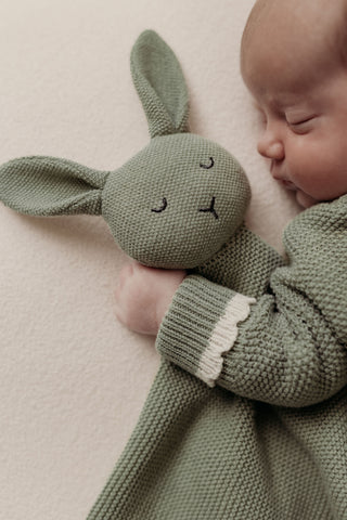 Sleeping baby cuddling sage green bunny comforter