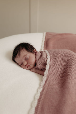 baby girl sleeping with pink knitted blanket