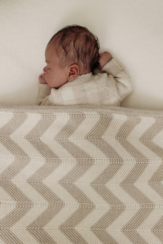 Sleeping baby with neutral chevron stripe knitted blanket