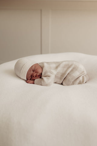 sleeping baby on beanbag wearing knitted romper and hat