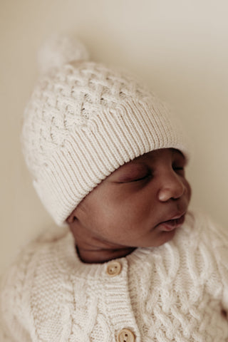 Baby wearing cable knit hat and cardigan