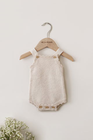 Knitted Baby Romper hanging on an Isla & Fraser hanger with flowers