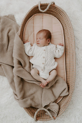 Sleeping Baby in a Moses Basket wearing Organic Cotton Cable Knit Baby Cardigan