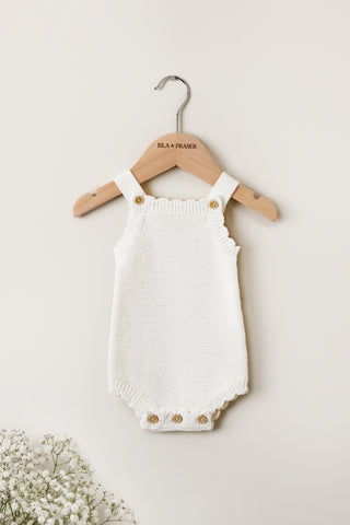 White knitted baby romper on a wooden Isla & Fraser hanger