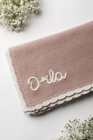 Rose pink knitted baby blanket with cream scalloped edge and embroidered name: Orla