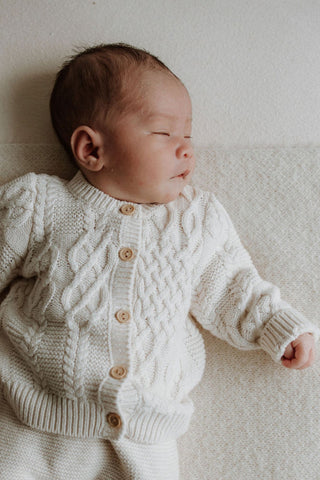 Sleeping baby wearing cable knitted cardigan