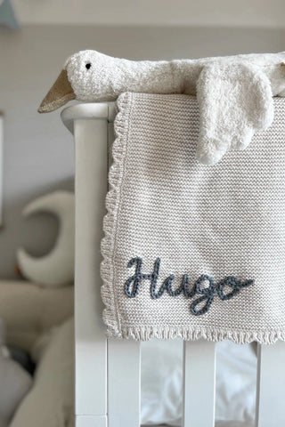 Baby cot with goose and embroidered 'Hugo' knitted blanket