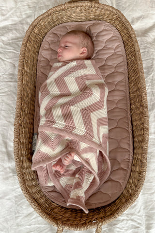Baby in Basket Swaddled in Rose and Cream Chevron Stripe Knitted Baby Blanket
