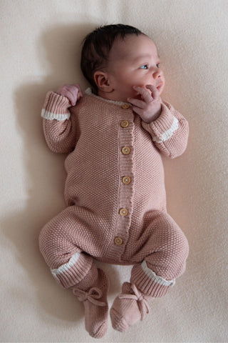 Baby in knitted pink romper and booties
