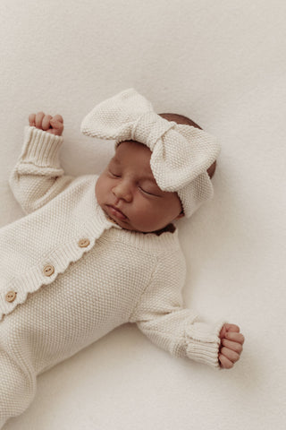 baby asleep on beanbag wearing a knitted hat and romper