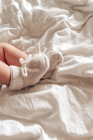 Crumpled Sheet with Baby Feet wearing Knitted Bow Booties