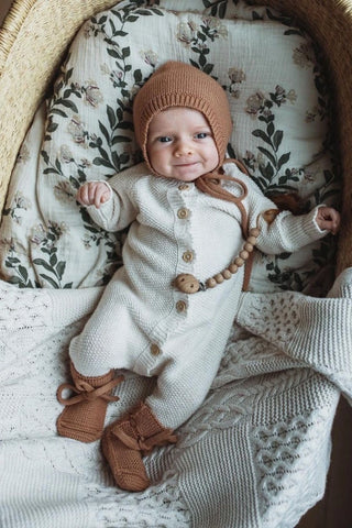 Baby in Basket on a Floral Sheet wearing Organic Cotton Moss Stitch Baby Romper, a bonnet and booties