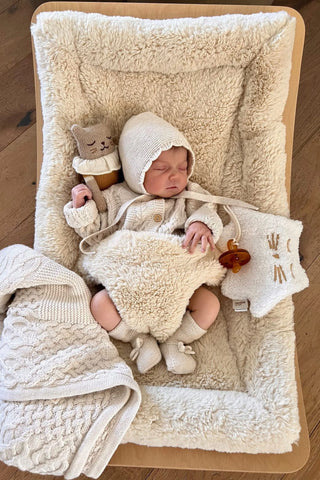 Sleeping baby in rocker wearing Knitted Baby Bonnet, Baby Cardigan and Baby Booties