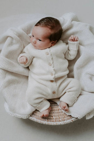 Newborn Baby in a basket lying on a blanket wearing Organic Cotton Moss Stitch Baby Romper