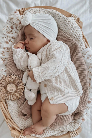 Sleeping Baby in Basket with 3 months old plaque, wearing Organic Cotton Cable Knit Baby Cardigan and Bloomers