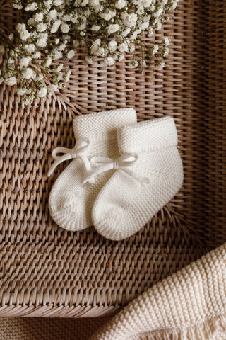 Milk White Baby Booties in a Basket with gypsophilia