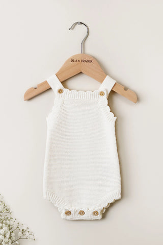 Milk White Baby Romper on an Isla & Fraser hanger on a white backdrop with gypsophilia
