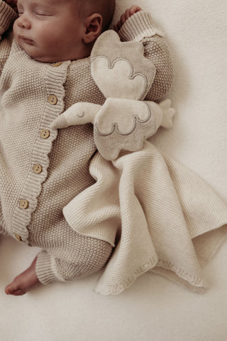 Sleeping baby with cream and grey knitted stork comforter