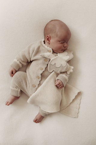 Sleeping baby with cream and grey knitted romper and stork comforter