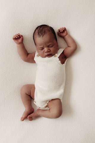 Sleeping newborn wearing white knitted romper