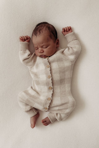 Sleeping baby wearing grey neutral check knitted romper