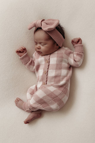 Baby wearing pink checkered romper and pink bow headband
