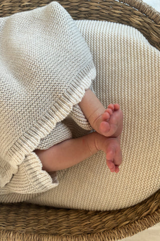 baby feet in moses basket wrapped in knitted blanket