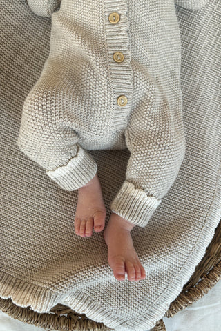 baby feet in knitted romper on knitted blanket