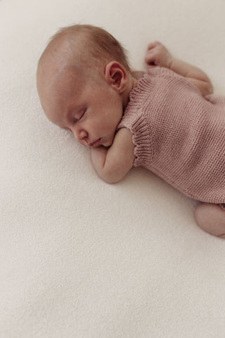 Sleeping baby wearing knitted pink romper
