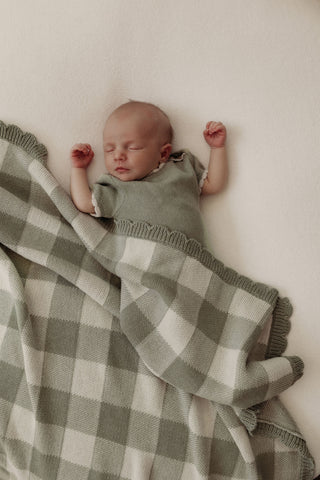 Baby wearing green romper with green check blanket