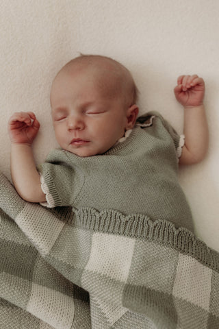 Baby wearing green romper with green check blanket