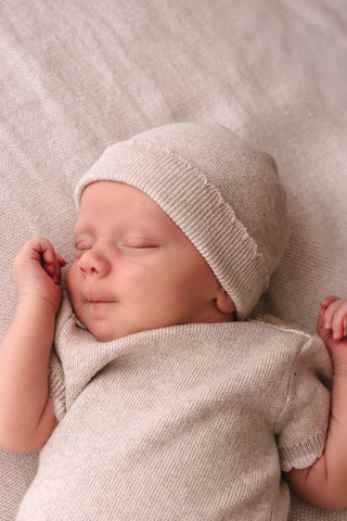 Sleeping baby wearing neutral knitted hat