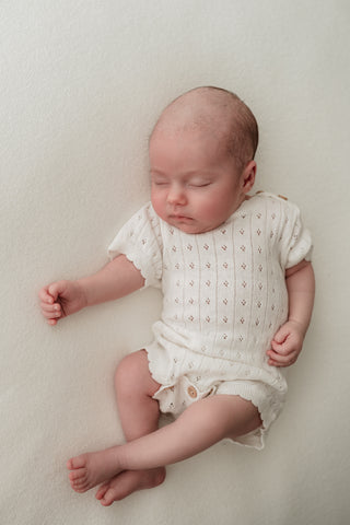 Baby wearing white pointelle bodysuit 