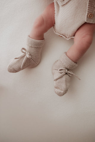 Baby's legs wearing grey knitted bow booties