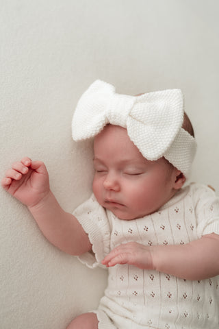 Baby wearing white bow headband