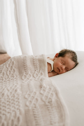 Sleeping baby under a cable knit blanket
