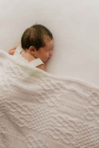 Sleeping baby under a cable knit blanket