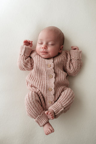 Sleeping baby wearing knitted pink romper