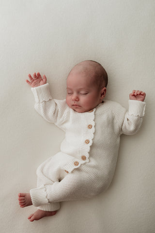 Baby sleeping wearing white button up knitted romper