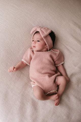 Baby wearing a knitted pink headband and bodysuit