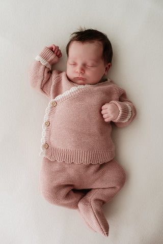 Baby wearing pink knitted wrap cardigan and footed trousers